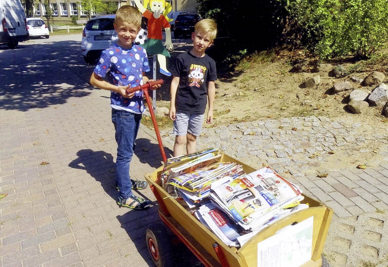 Kinder mit einem Bollerwagen voller Altpapier