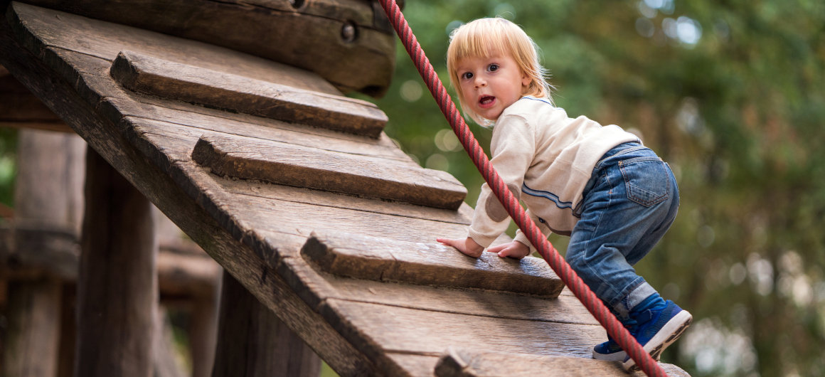 Kind klettert auf dem Spielplatz