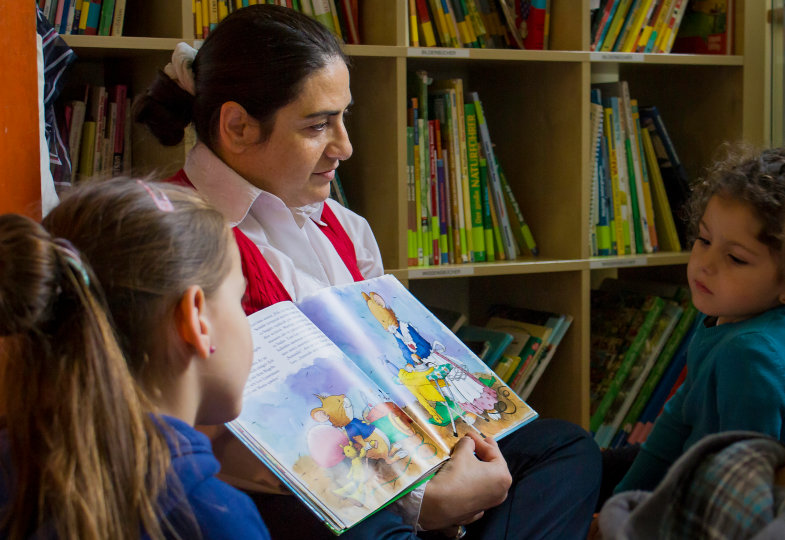 Person liest Kindern etwas aus einem Buch vor