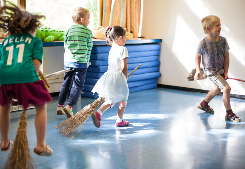 Wilde Feger: Mit teils selbst gestalteten Hexenbesen tanzen die Kinder durch den Raum