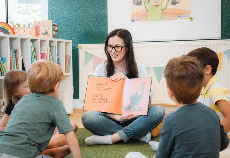 Person zeigt einer Gruppe von Kindern ein Buch