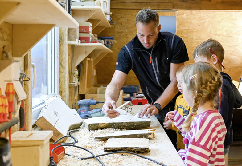 Kinder mit einem Handwerker in der Werkstatt