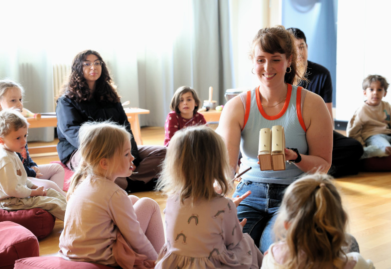 Kinder und Erwachsene sitzen im auf dem Boden im Kreis.
