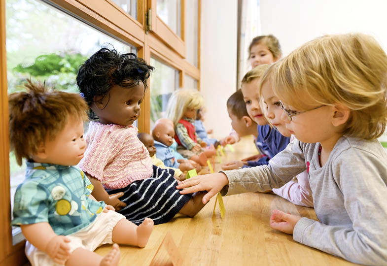 Kinder in einem Innenraum mit Puppen
