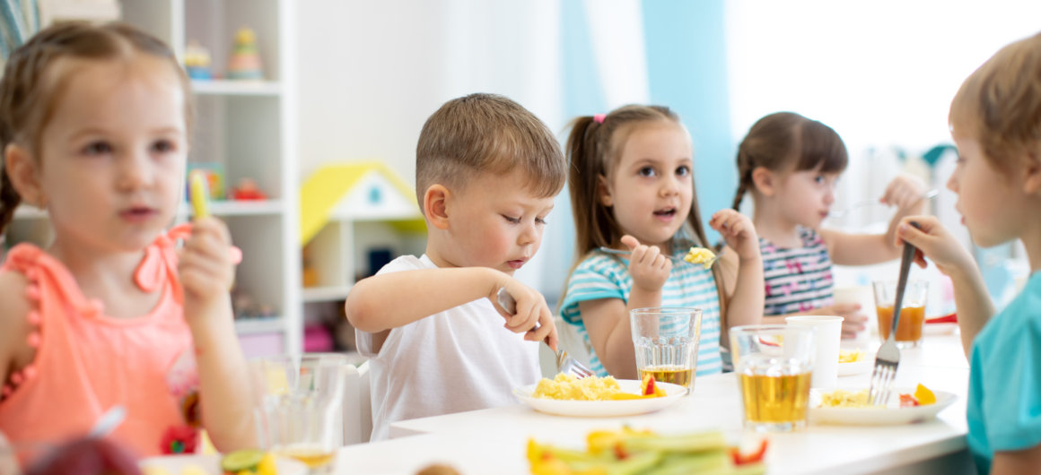 Kinder sitzen am Tisch und essen