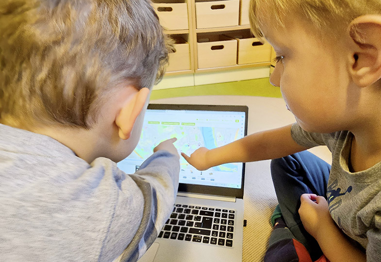 Zwei Kinder zeigen auf einen Laptop