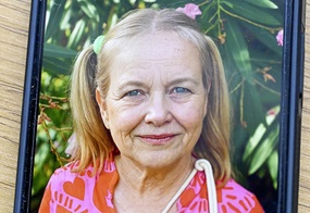 Auf einem Tisch liegt ein Handy, auf dessen Bildschirm ein Bild eines Kindes zu sehen ist, das digital gealtert wurde.