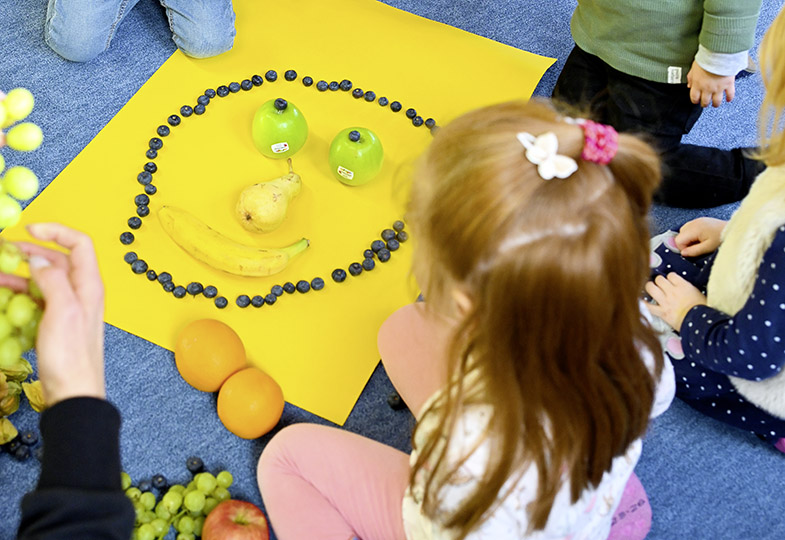 Kinder legen Gesichter aus Obst