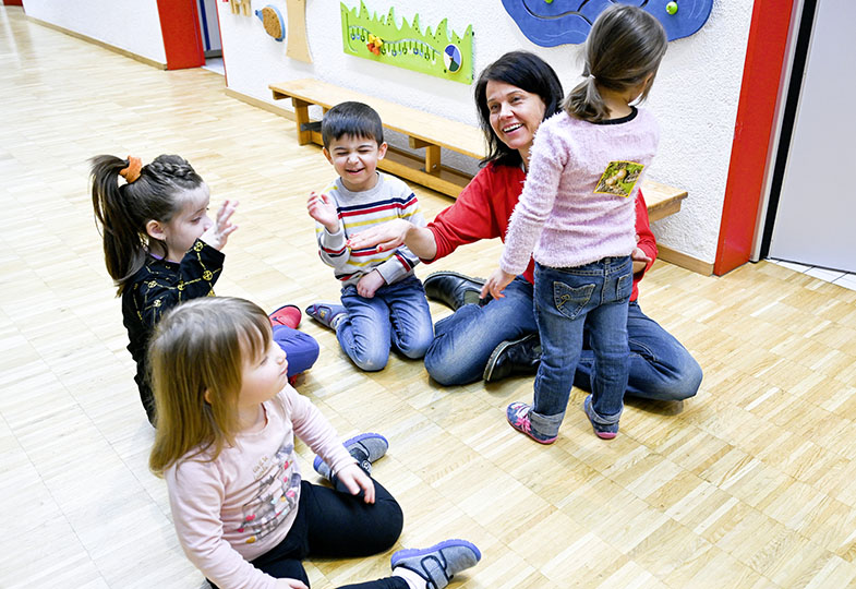 Kinder sitzen im Kreis auf dem Boden