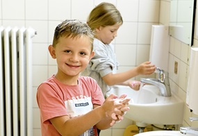 Zwei Kinder stehen im Badezimmer und waschen sich gründlich die Hände.