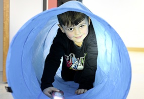 Ein Junge geht mit einer Taschenlampe durch einen blauen, faltbaren Spieltunnel.