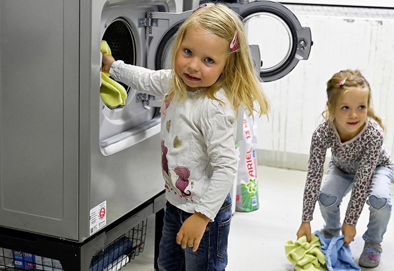 Kinder befüllen die Waschmaschine