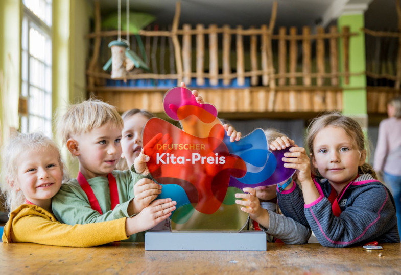 Kinder halten das Logo des Deutschen Kita-Preises