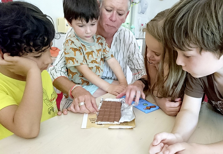 Kinder sitzen um eine Tafel Schockolade