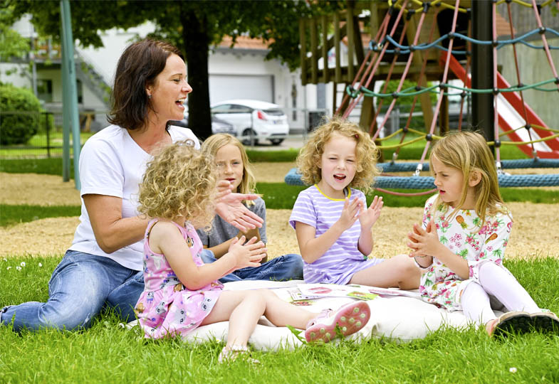 Kinder sitzen auf einer Decke auf dem Spielplatz
