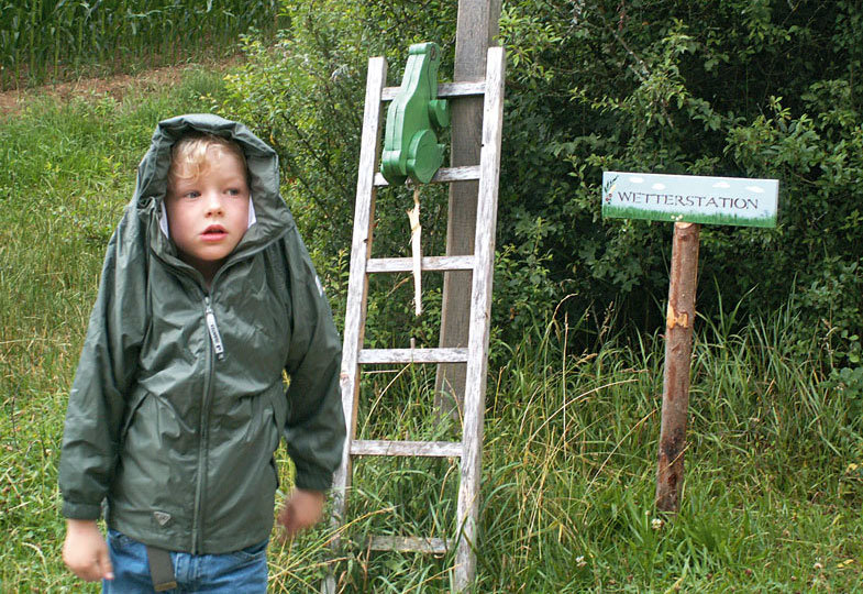 Kinder in Regenkleidung im Garten