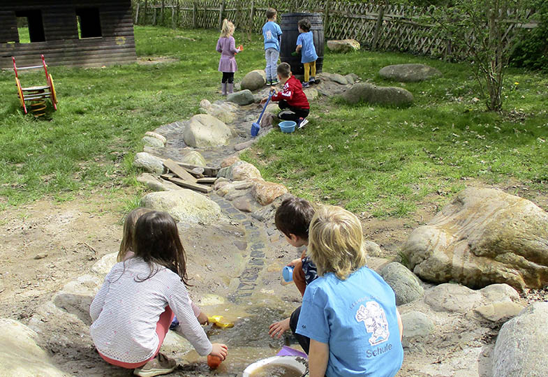 Kinder spielen am Wasserlauf
