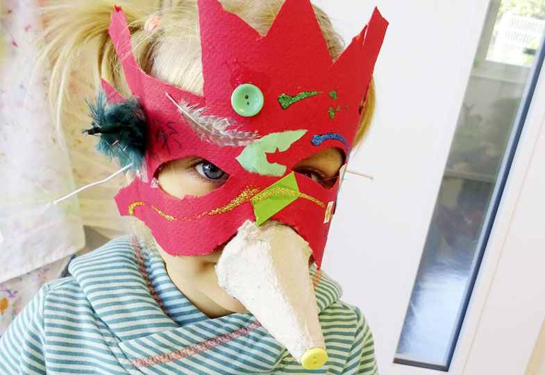 Kind trägt eine gebastelte Maske