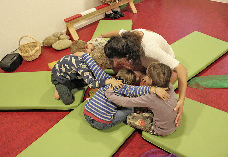 Kinder und eine erwachsene Person umarmen sich 
