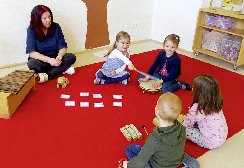 Kinder sitzen mit einer erwachsenen Person im Innenraum auf dem Boden