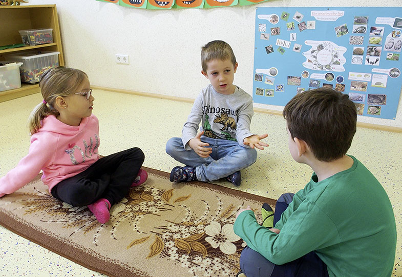Drei Kinder sitzen auf deinem Teppich