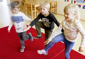 Drei Kinder heben jeweils einen Fuß, um ihre Füße zu zeigen.