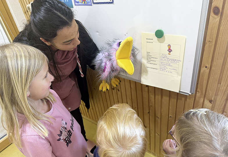 Kinder, die einer erwachsenen Person mit einer Handpuppe zuschauen