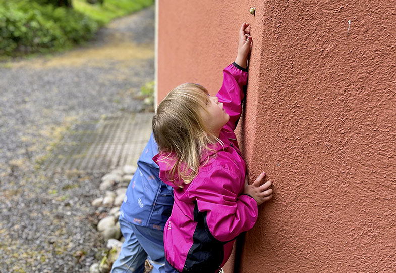 Kind an einer Hauswand