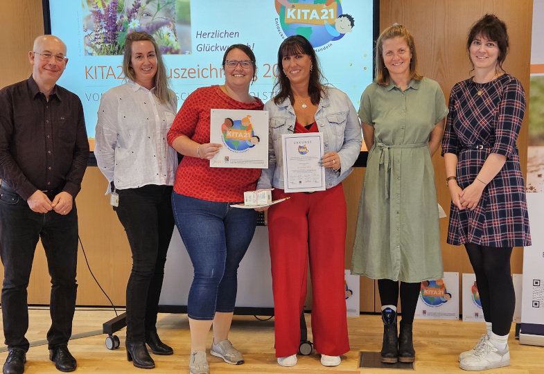 Mehrere Personen stehen nebeneinander und lächeln in die Kamera.