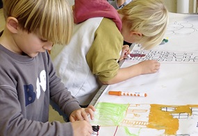 Auf einem Plakat skizzieren zwei Kinder ihre Zukunftshäuser.