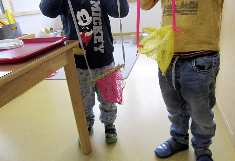 Zwei Kinder mit einer Tasche, gebastelt aus Verpackungsnetzen