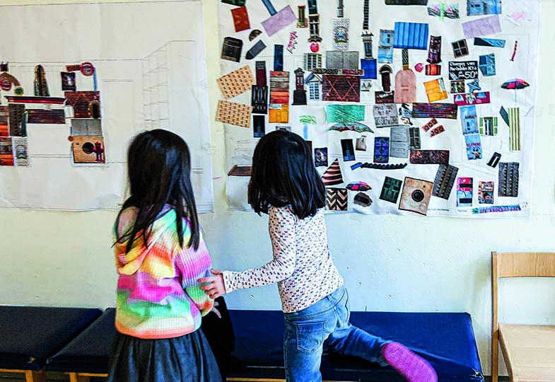 Zwei Kinder vor einer Wand mit Bilder