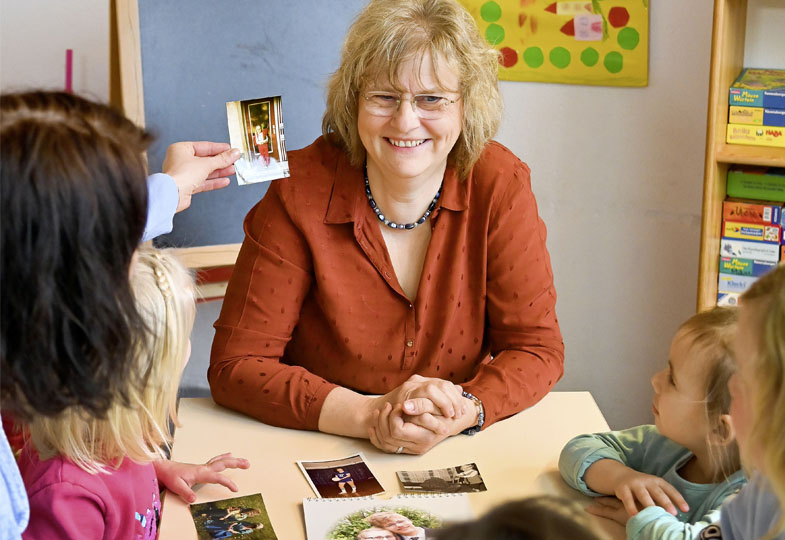 Kinder sprechen mit einer älteren Person über Fotos