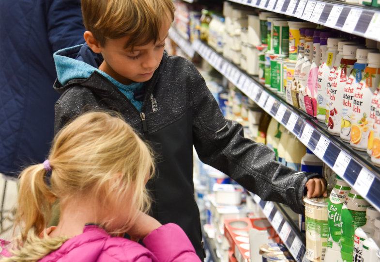 Kinder schauen sich Verpackungen im Supermarkt an