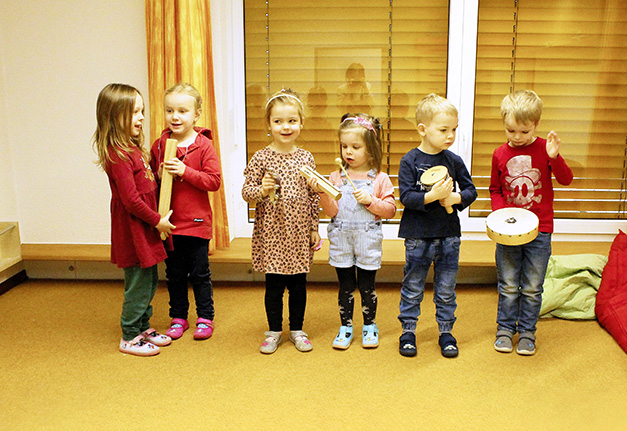 Kinder stehen in einer Reihe und musizieren