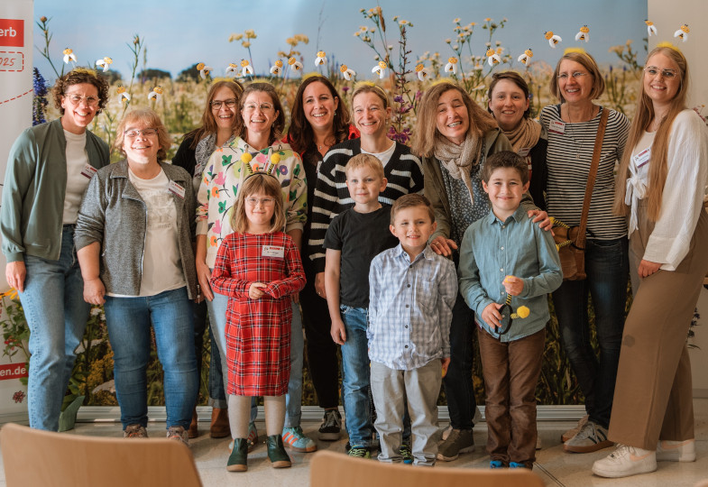 Kinder und Erwachsene stehen nebeneinander und blicken in die Kamera.