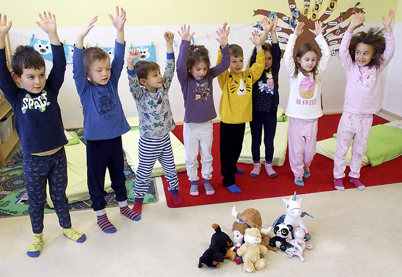 Kinder stehen in einer Reihe und heben die Hände nach oben