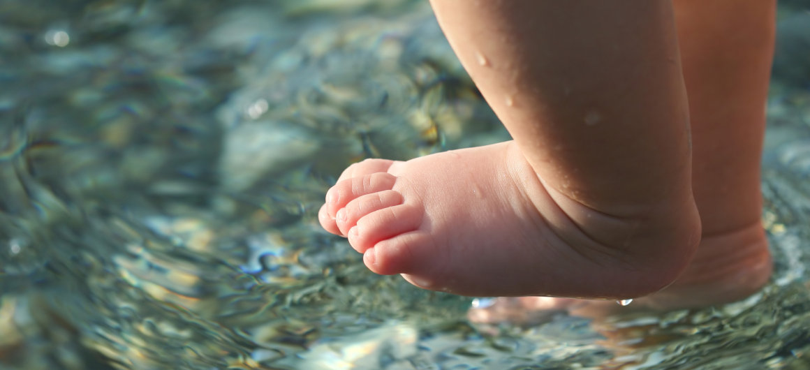 Kind steht mit den Füßen im Wasser