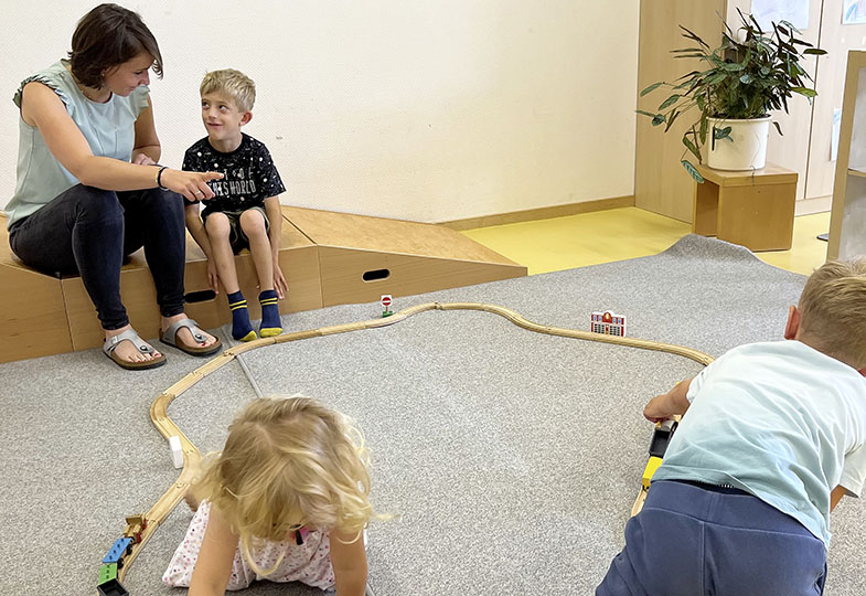 Kinder spielen mit einer Holzeisenbahn
