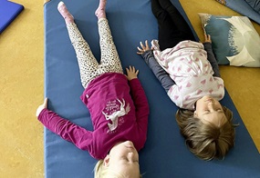 Zwei Kinder liegen auf einer Matte