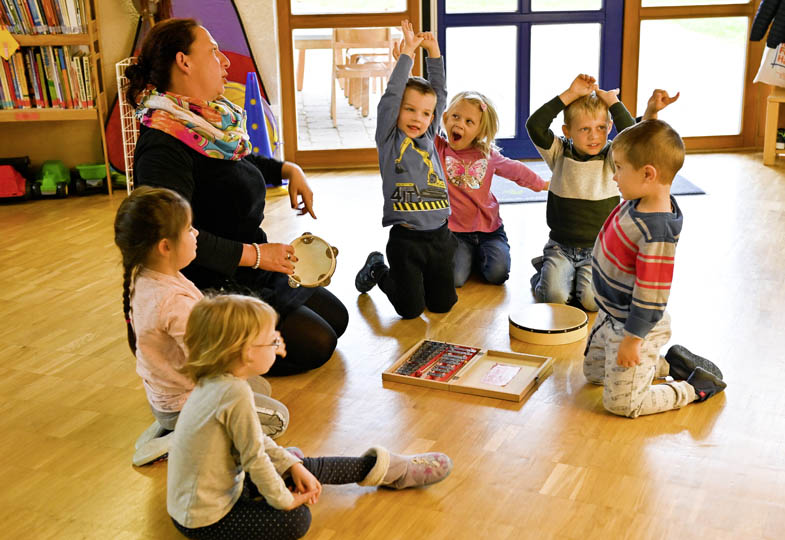 Kinder sitzen im Kreis und musizieren