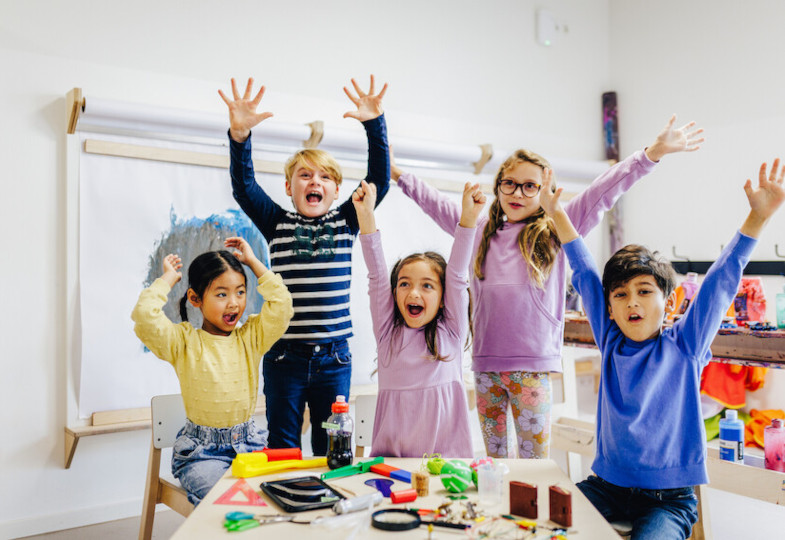 Mehrere Kinder stehen nebeneinander und strecken ihre Arme in die Luft.