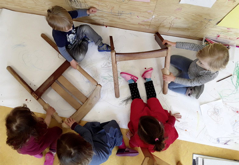 Kinder sitzen auf einem großen Stück Papier