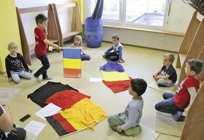 Kinder sitzen mit Länderflaggen in einem Raum 