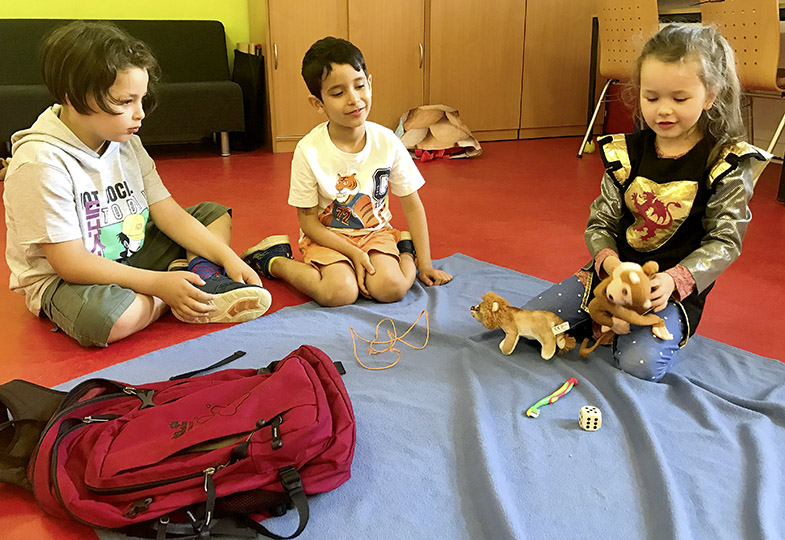 Drei Kinder sitzen auf dem Boden im Kreis