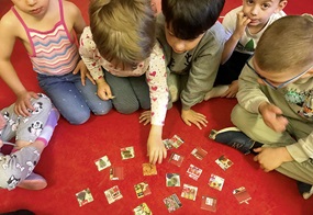 Die Kinder sitzen im Halbkreis, und in der Mitte liegen verschiedene Kärtchen, die sie den passenden zuordnen müssen.