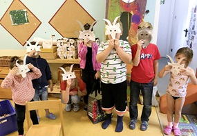 Die Kinder halten verschiedene selbstgebastelte Masken vor ihr Gesicht von einer Ziege oder einem Wolf.