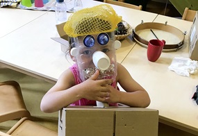 Mit recycelten Materialien hat ein Kind eine Maske und einen Körper gebaut, in den es hineinschlüpfen kann.