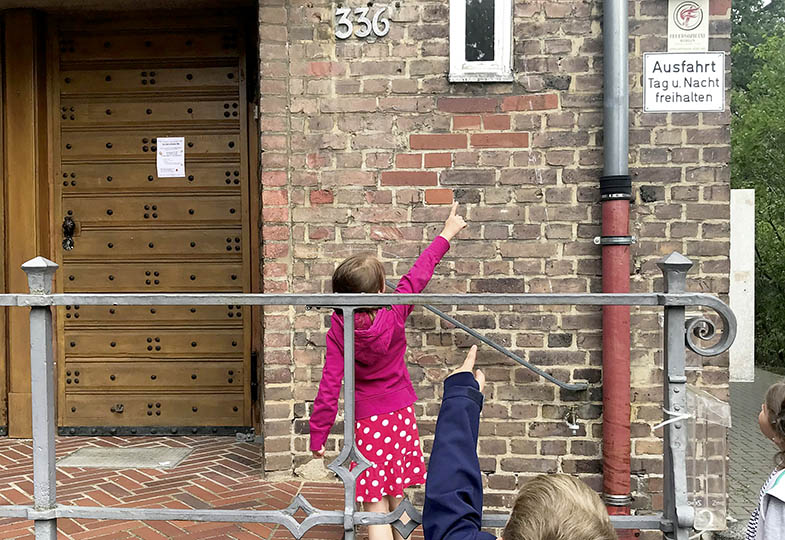 Kinder zeigen auf eine Hauswand