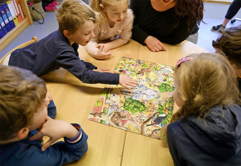 Kinder sitzen an einem Tisch und schauen sich ein Bild an